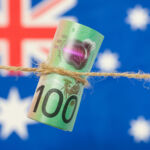Australia’s economic reforms could boost agricultural investment Close up of an Australian one hundred dollar bill tied in string. Australian flag in background.