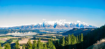 The dramatic scenery of New Zealand's South Island. Large mountains in the distance with pine forests and plains stretching out in every direction on a clear winters day