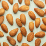 Almonds pattern in front of the neutral blue background. Almond seamless pattern in front of the neutral background top view.