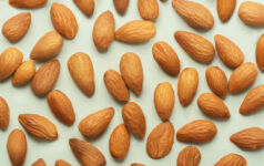 Almonds pattern in front of the neutral blue background. Almond seamless pattern in front of the neutral background top view.