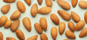 Almonds pattern in front of the neutral blue background. Almond seamless pattern in front of the neutral background top view.