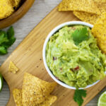 A bowl of guacamole with a tortilla chip in it