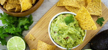 A bowl of guacamole with a tortilla chip in it