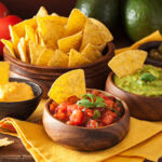 A table laid with a bowl of Tortilla chips and a selection of dips