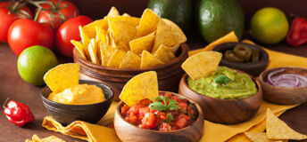 A table laid with a bowl of Tortilla chips and a selection of dips
