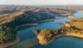 This aerial drone image showcases Mount Bold Reservoir Dam, the largest reservoir in South Australia, nestled within the picturesque Adelaide Hills. The footage captures the expansive forested landscape, winding waterways, and the massive dam wall from a high vantage point. Surrounded by protected catchment zones and scenic lookouts, the area is known for its vital role in water storage and stunning natural beauty.