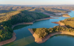 This aerial drone image showcases Mount Bold Reservoir Dam, the largest reservoir in South Australia, nestled within the picturesque Adelaide Hills. The footage captures the expansive forested landscape, winding waterways, and the massive dam wall from a high vantage point. Surrounded by protected catchment zones and scenic lookouts, the area is known for its vital role in water storage and stunning natural beauty.