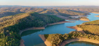 This aerial drone image showcases Mount Bold Reservoir Dam, the largest reservoir in South Australia, nestled within the picturesque Adelaide Hills. The footage captures the expansive forested landscape, winding waterways, and the massive dam wall from a high vantage point. Surrounded by protected catchment zones and scenic lookouts, the area is known for its vital role in water storage and stunning natural beauty.